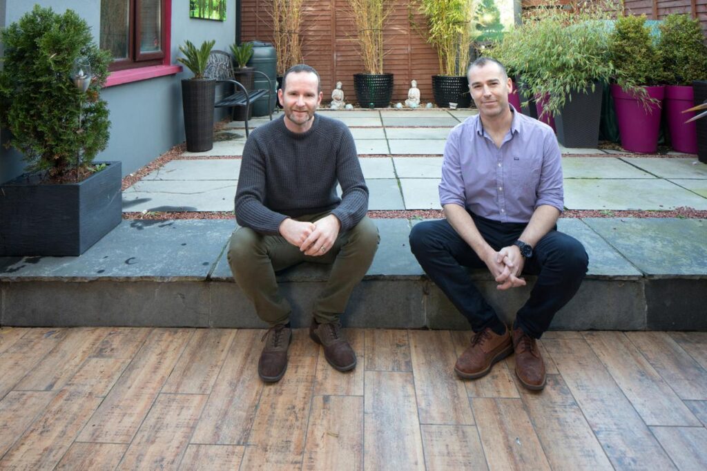 Brian (left) and Shane in their garden. The wood-effect tiles are continued from indoors to the outside, while the building on the left of the photo is the former garage, now the utility room